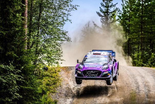 world rally race car on gravel road in forest