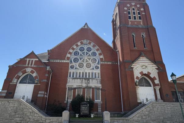 The fron of historical brick FIrst Baptist Church with ornate windows and tower