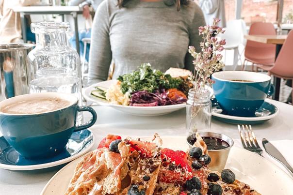 woman sits at table smiling down at her food at Southern Squeeze