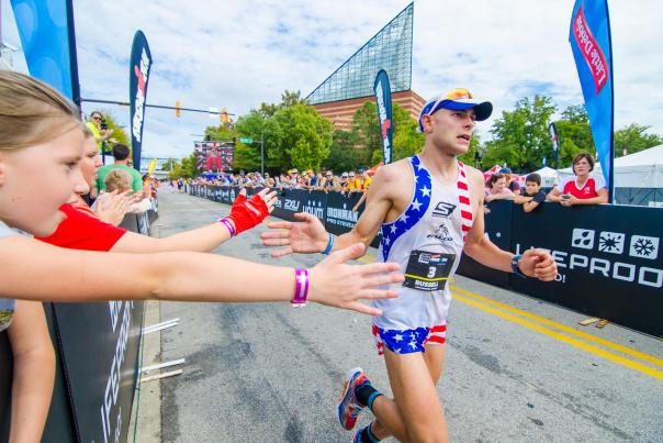 Person high fives spectators before crossing the finish line at Ironman Chattanooga